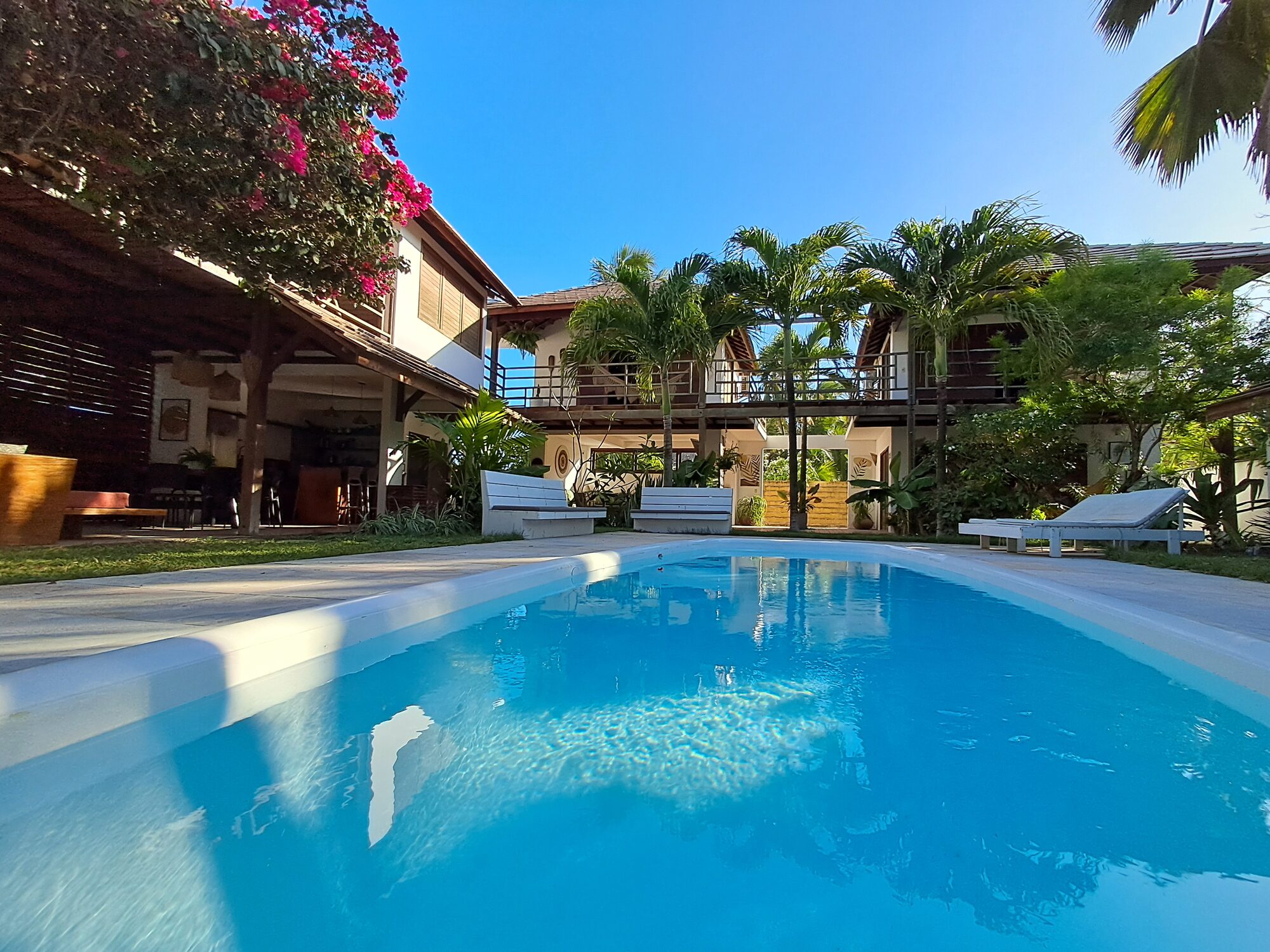 Piscine de Casa Guarani 4 chambres avec bougainvillées et palmiers au coucher du soleil